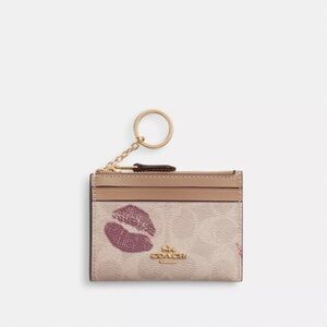 MINI ID SKINNY CASE IN SIGNATURE CANVAS WITH LIPS PRINT
Color: IM/Sand Multi